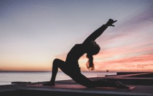 woman doing yoga on dock by water