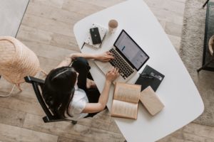 woman researching on laptop with books